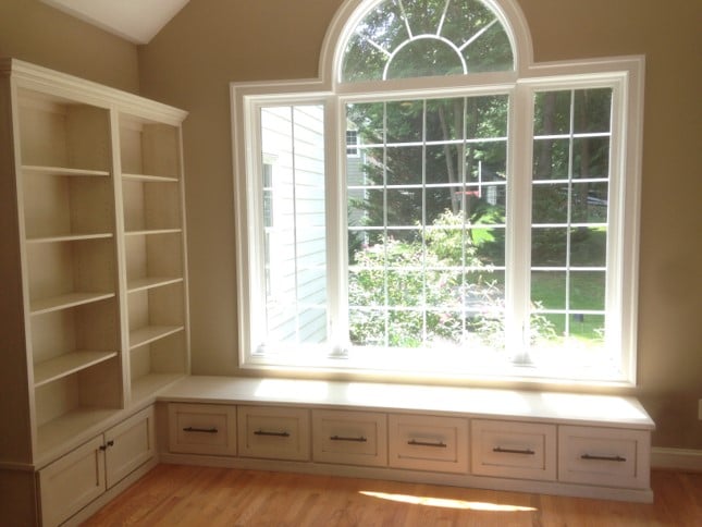 white built-in cabinets by a large window